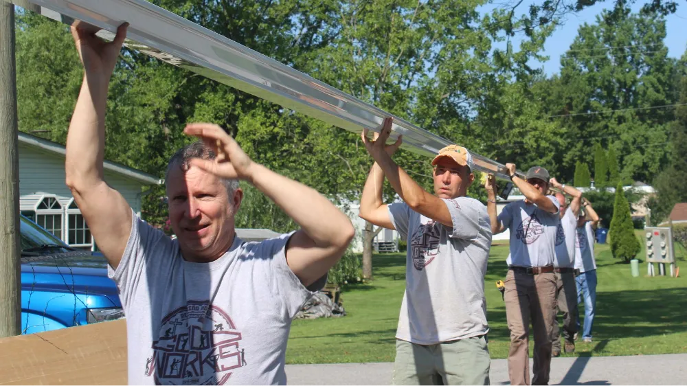 A Good Works team carrying a long metal beam