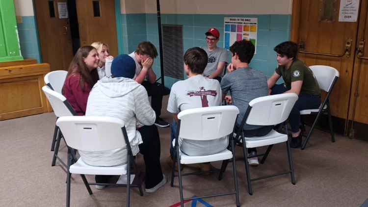 A group of young people meeting in a circle in a church basement